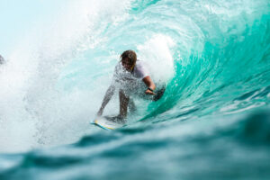 Surfer riding a wave near luxury beachfront properties by SKHAI