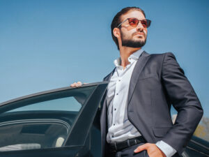 Stylish man in a suit beside luxury car, representing SKHAI luxury real estate.