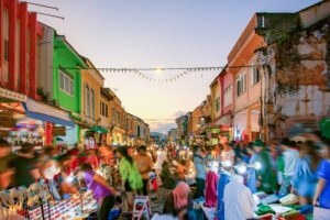 Vibrant street market scene at dusk with colorful buildings and bustling crowds