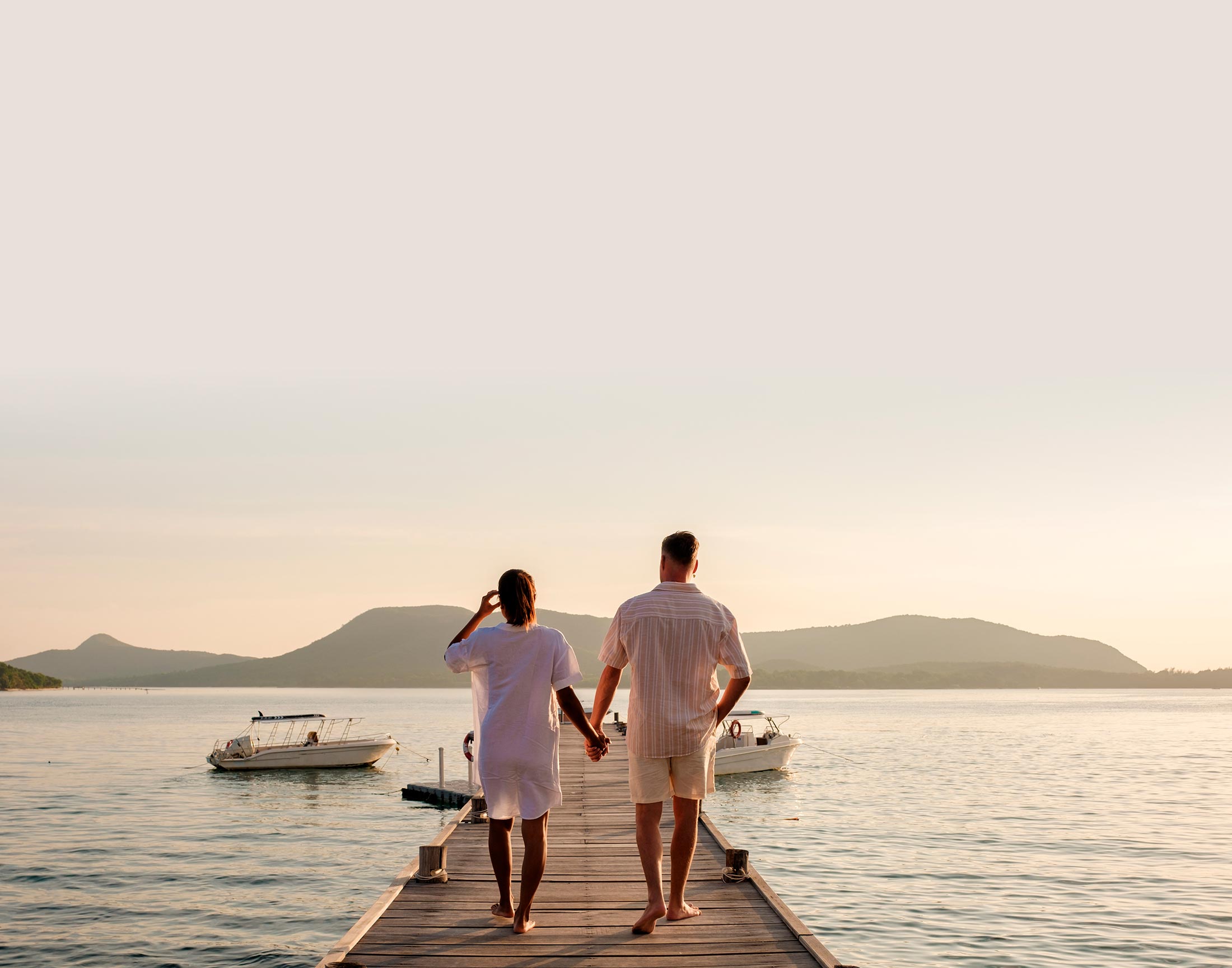 Couple walking hand-in-hand on a dock at sunset, featured in Home > Intro (video)