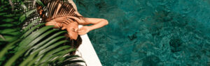 Woman relaxing by a luxurious pool surrounded by lush greenery